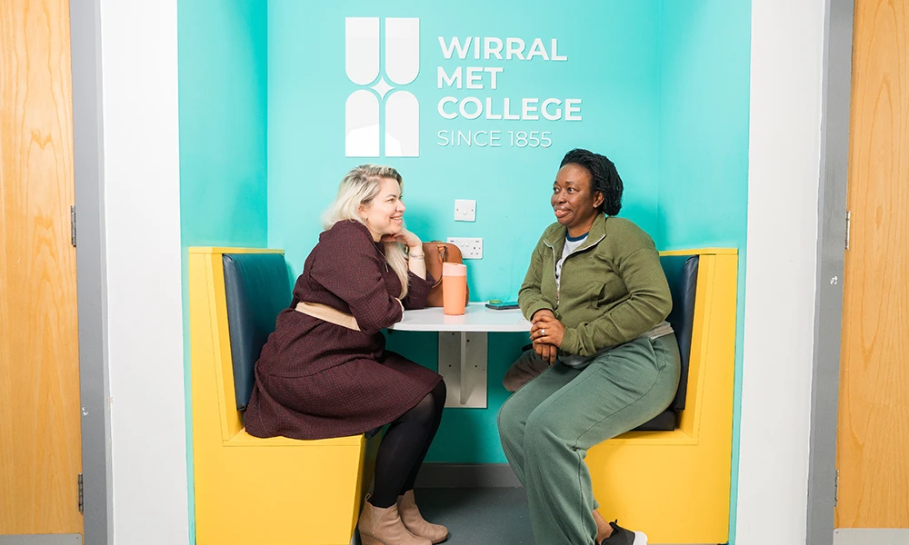 two women sat on a yellow bench opposite eachother