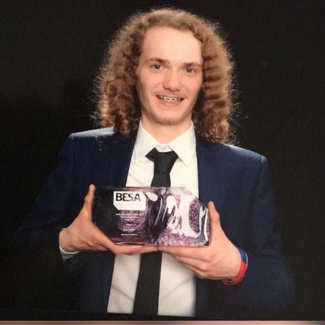 Wirral Met Electrical Engineering student standing wearing a suit and holding a BESA Award in 2017