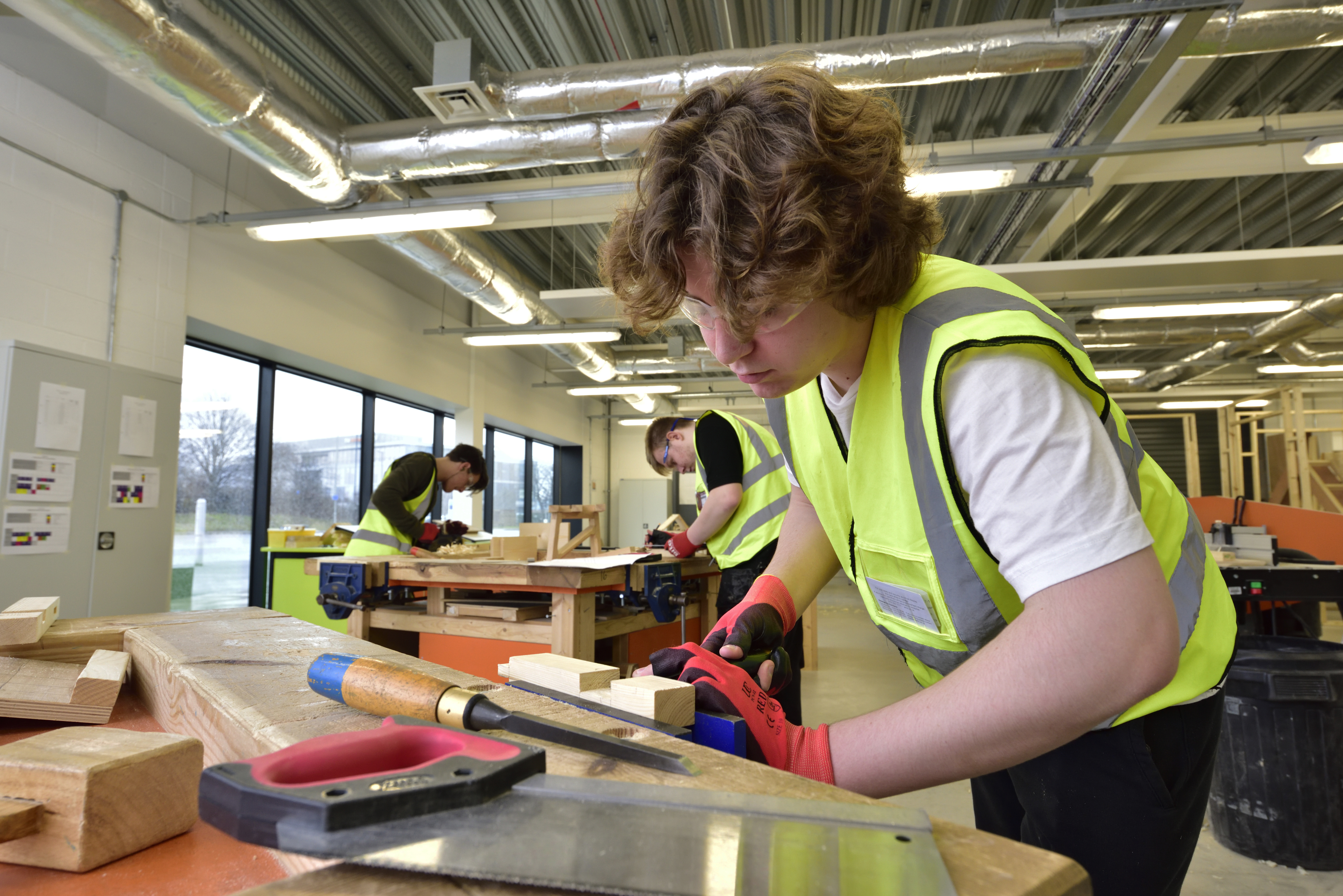Wirral Met joinery student working in a Hi-Vis jacket at Wirral Waters Campus