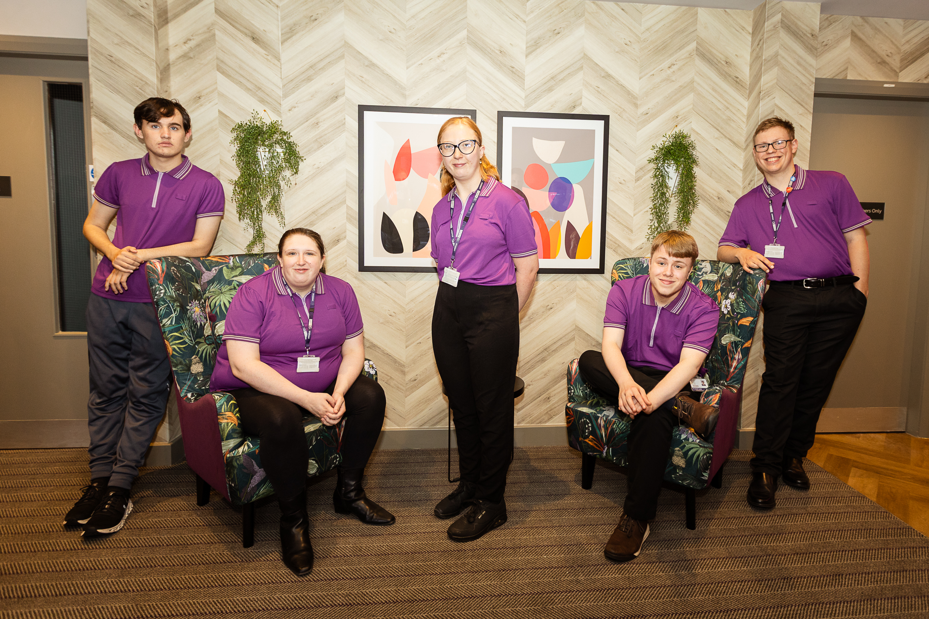 5 students in purple uniforms sat on chairs
