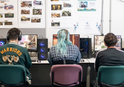 Three Computing And IT Students Wearing Virtual Reality Headsets In Classroom