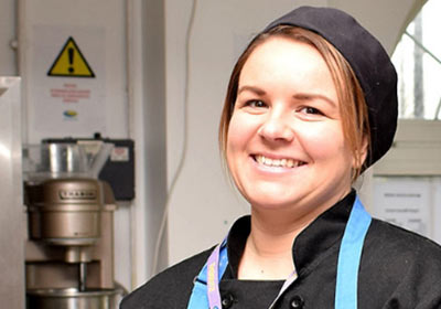 Female Hospitality And Catering Student Standing Inside Training Kitchen