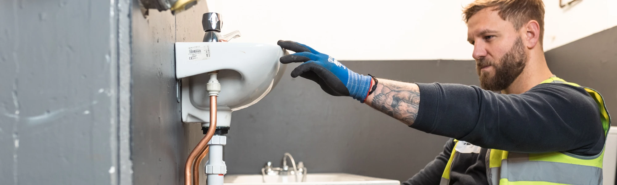 Male in hi vis fixing a sink