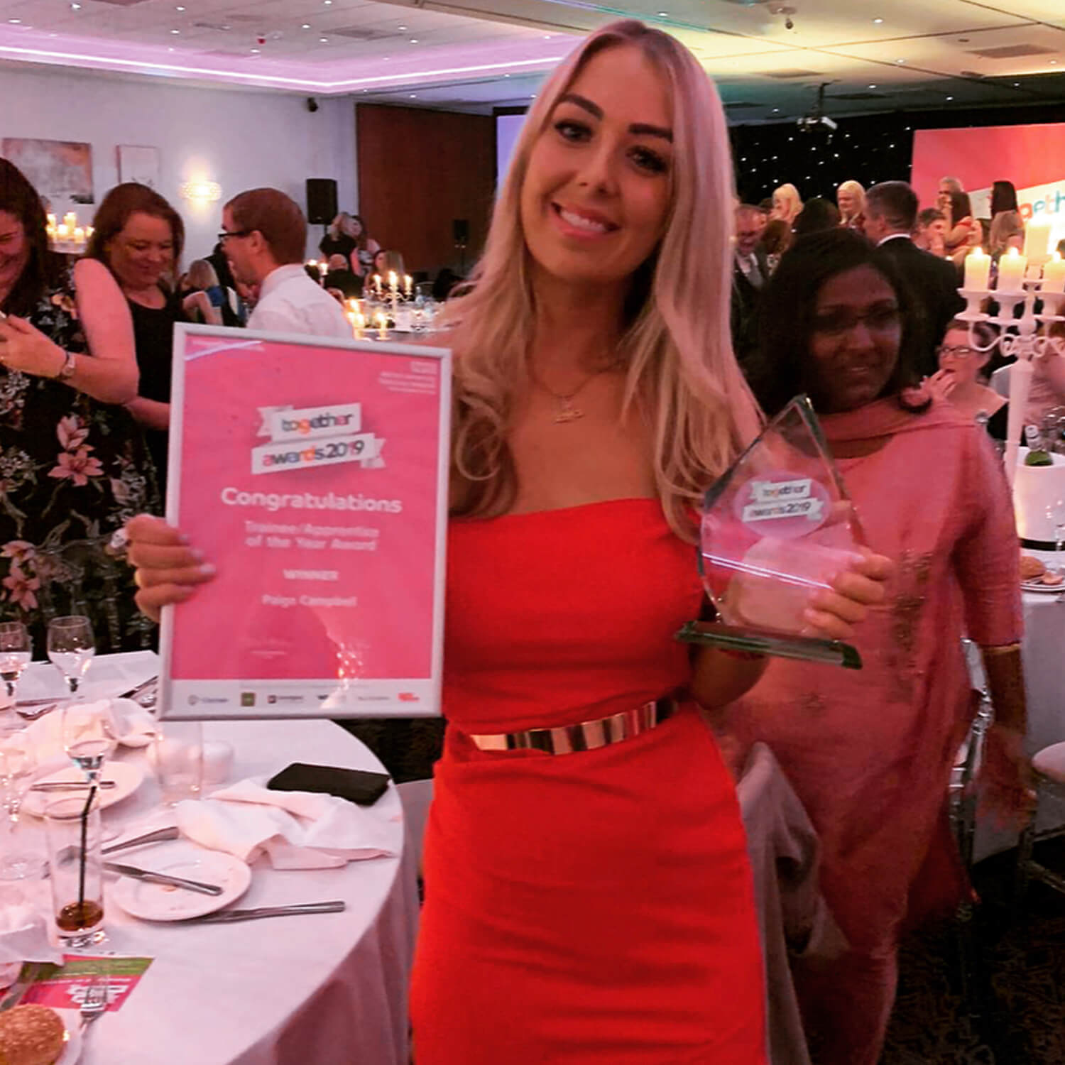 Woman in red dress holding certificate and award at Wirral University Teaching Hospital's annual staff awards