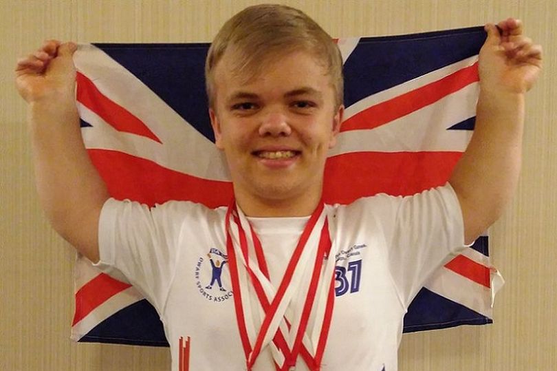Wirral Met sport student holding the union flag and wearing a white T-Shirt and three medals